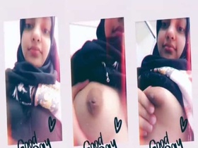 Watch a young woman in a hijab reveal her large breasts on camera